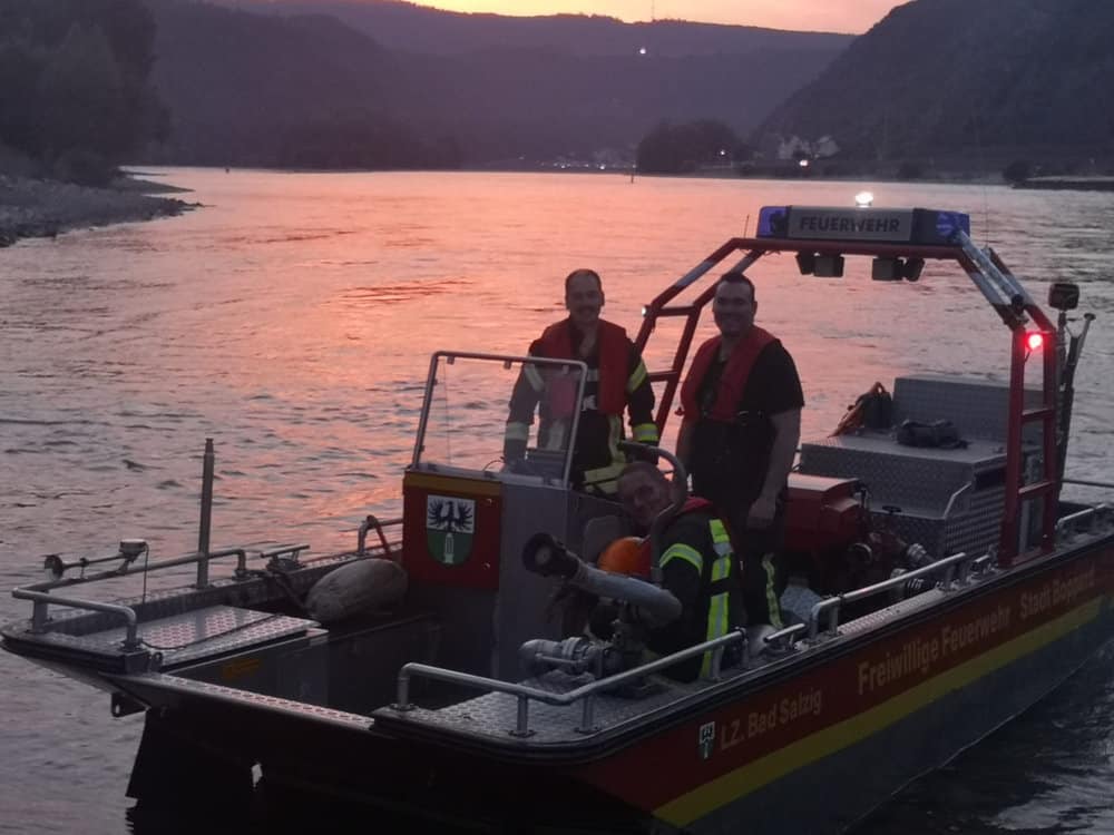 Feuerwehrboot mit Einsatzkräften auf dem Rhein bei Sonnenuntergang