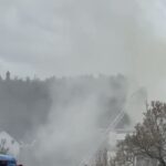 Feuerwehreinsatz mit dichtem Rauch über Wohngebäuden und Drehleiter im Einsatz